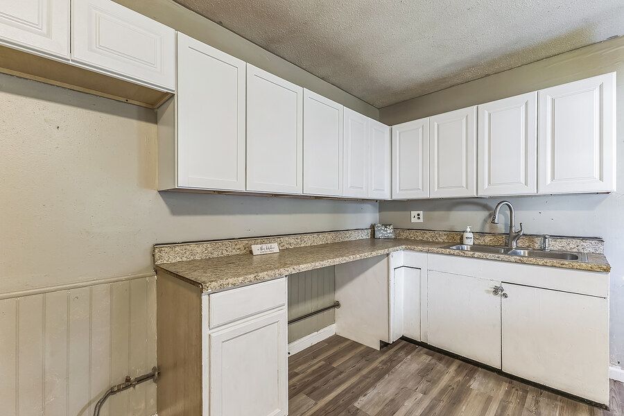 White kitchen cabinets with granite countertops, undermount sink, and hardwood floors in a bright, modern kitchen.