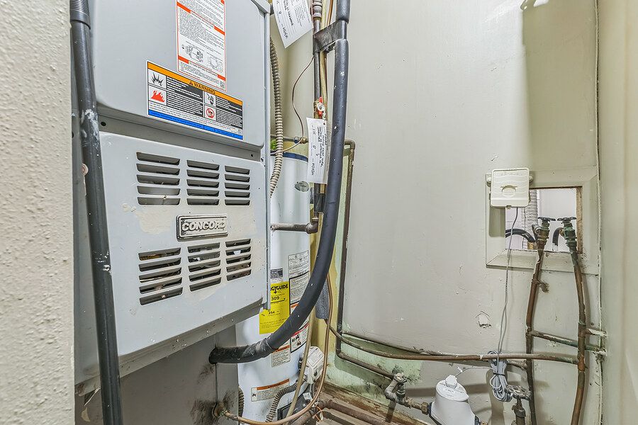 Utility closet featuring HVAC system, water heater, and exposed pipes and wiring.