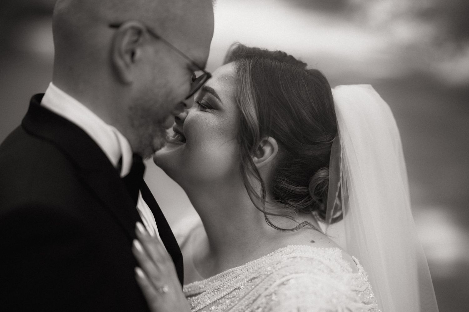 Black and white photo of a bride and groom sharing a romantic kiss on their wedding day.