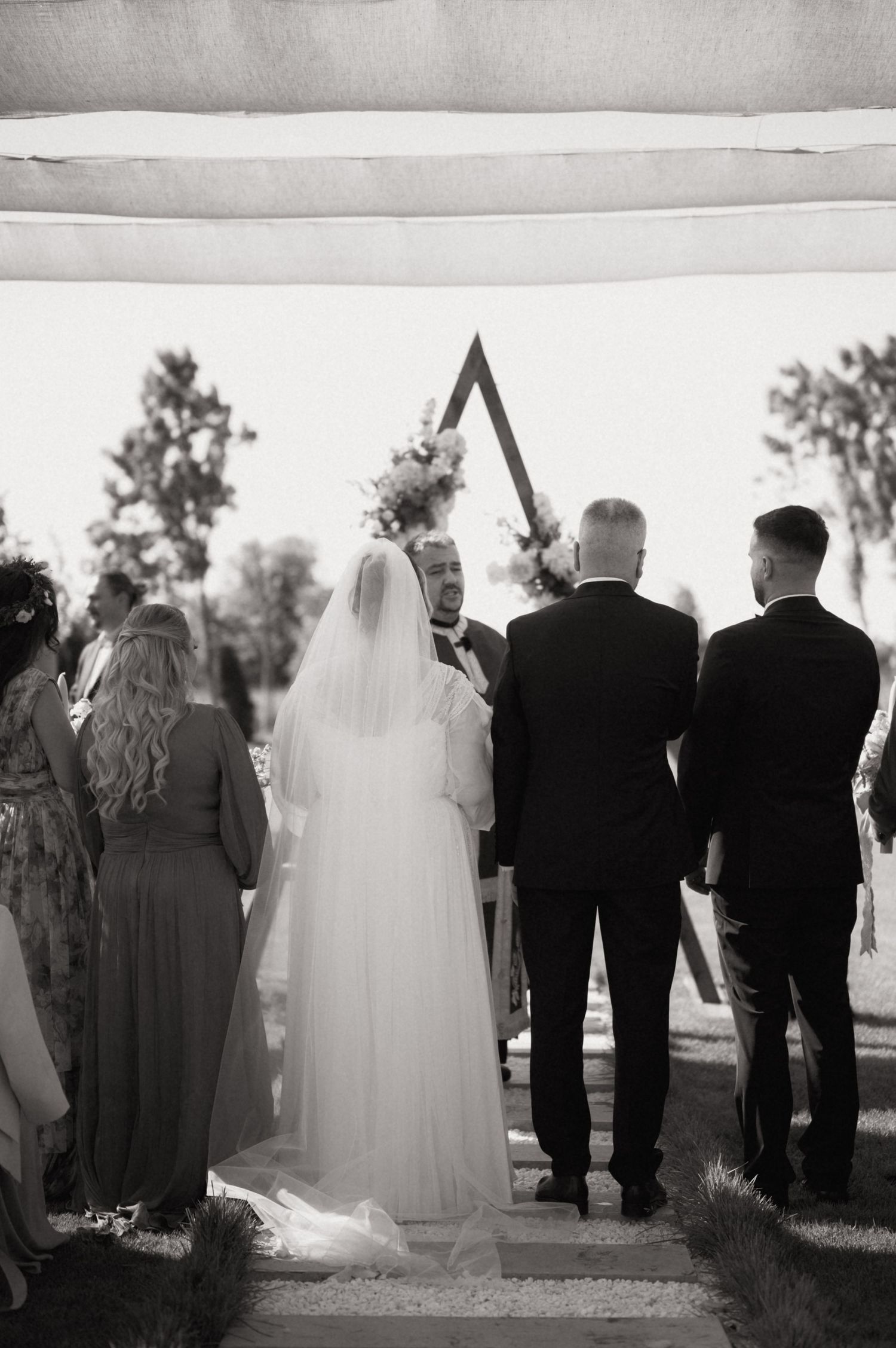 Black and white photo of a bride and groom standing at the altar during an outdoor wedding ceremony.