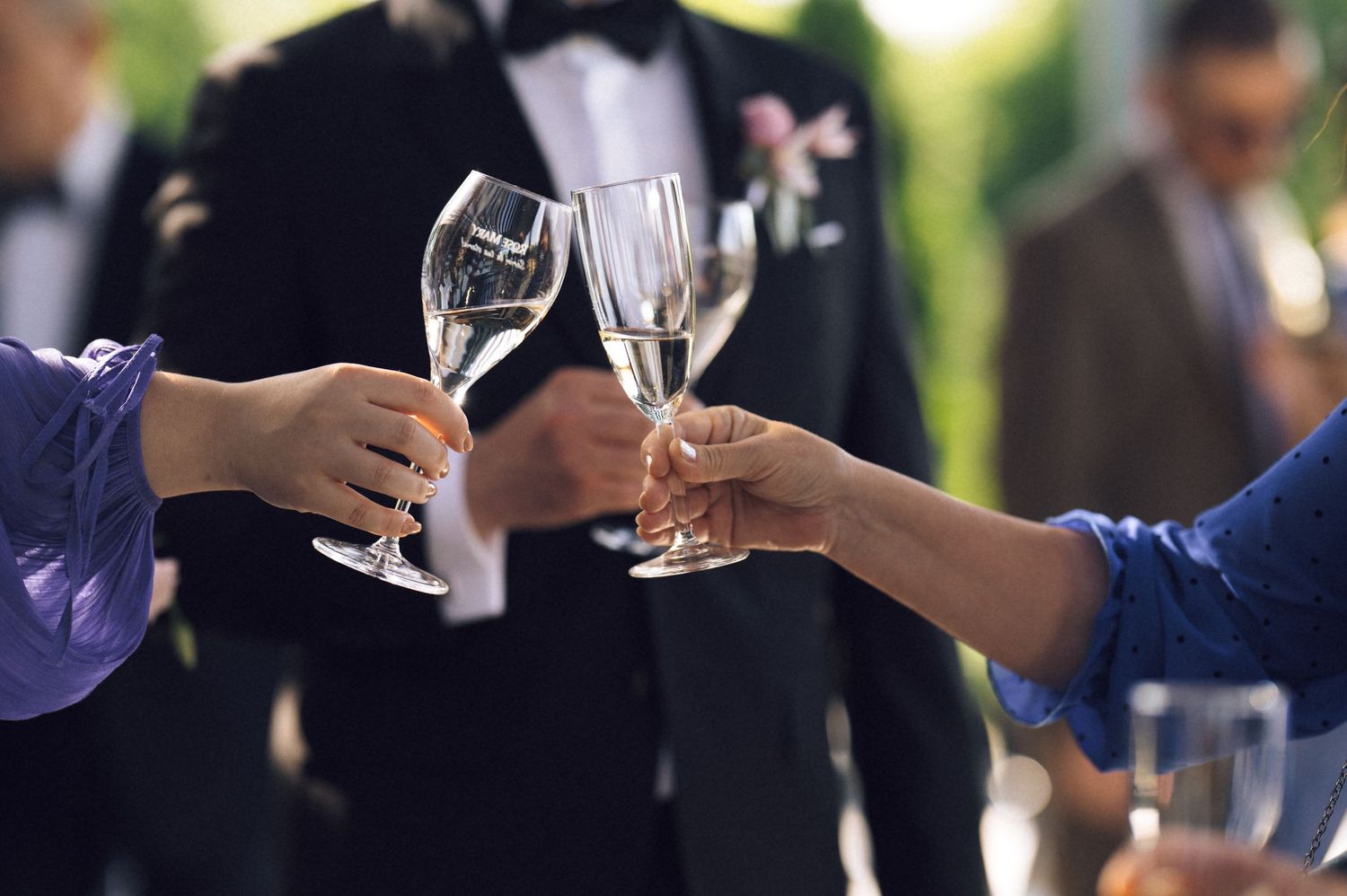 Guests clinking champagne glasses in a toast at an elegant outdoor wedding celebration.