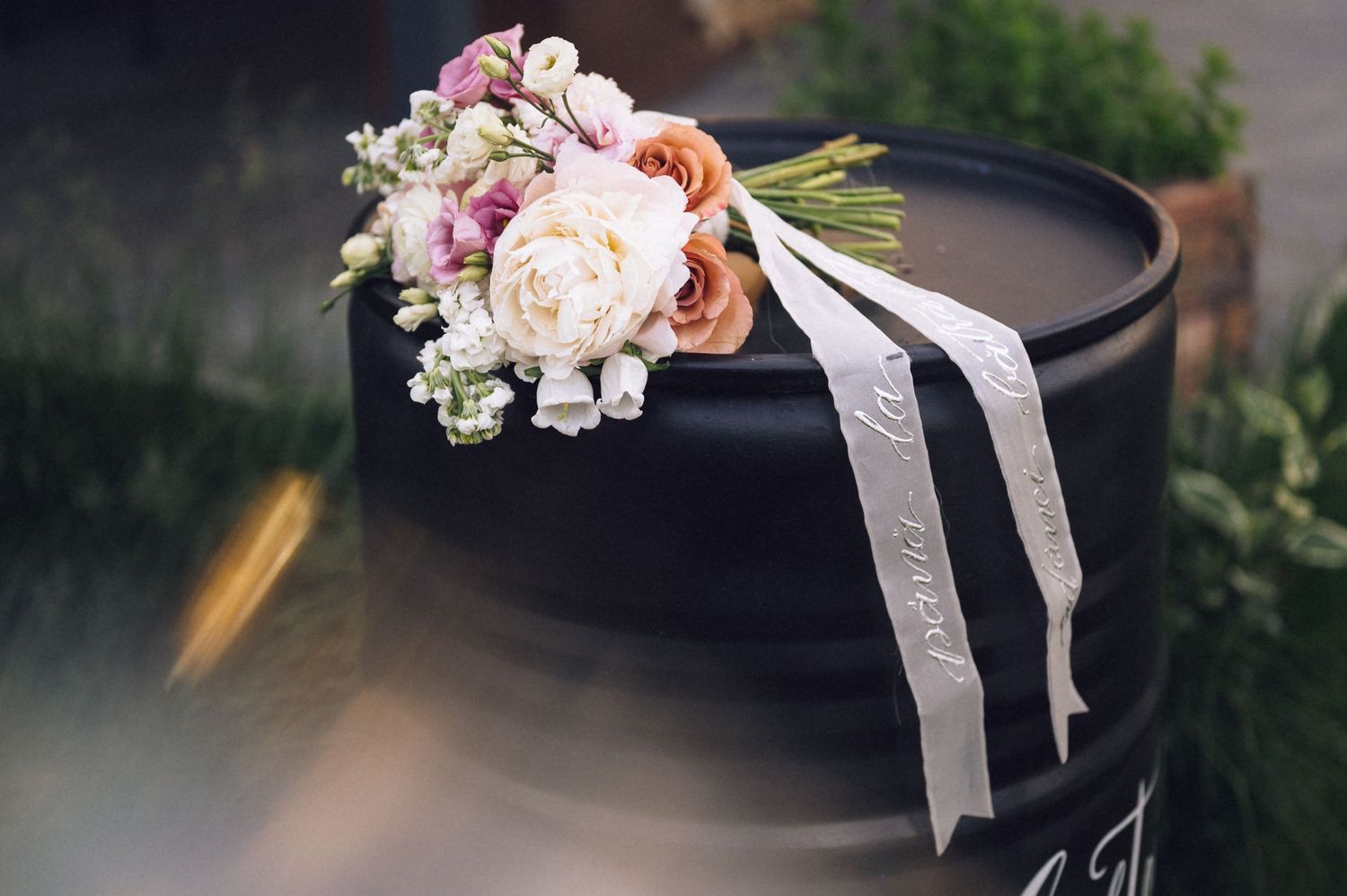 Elegant bridal bouquet with pink and white roses on a black surface with a white ribbon.