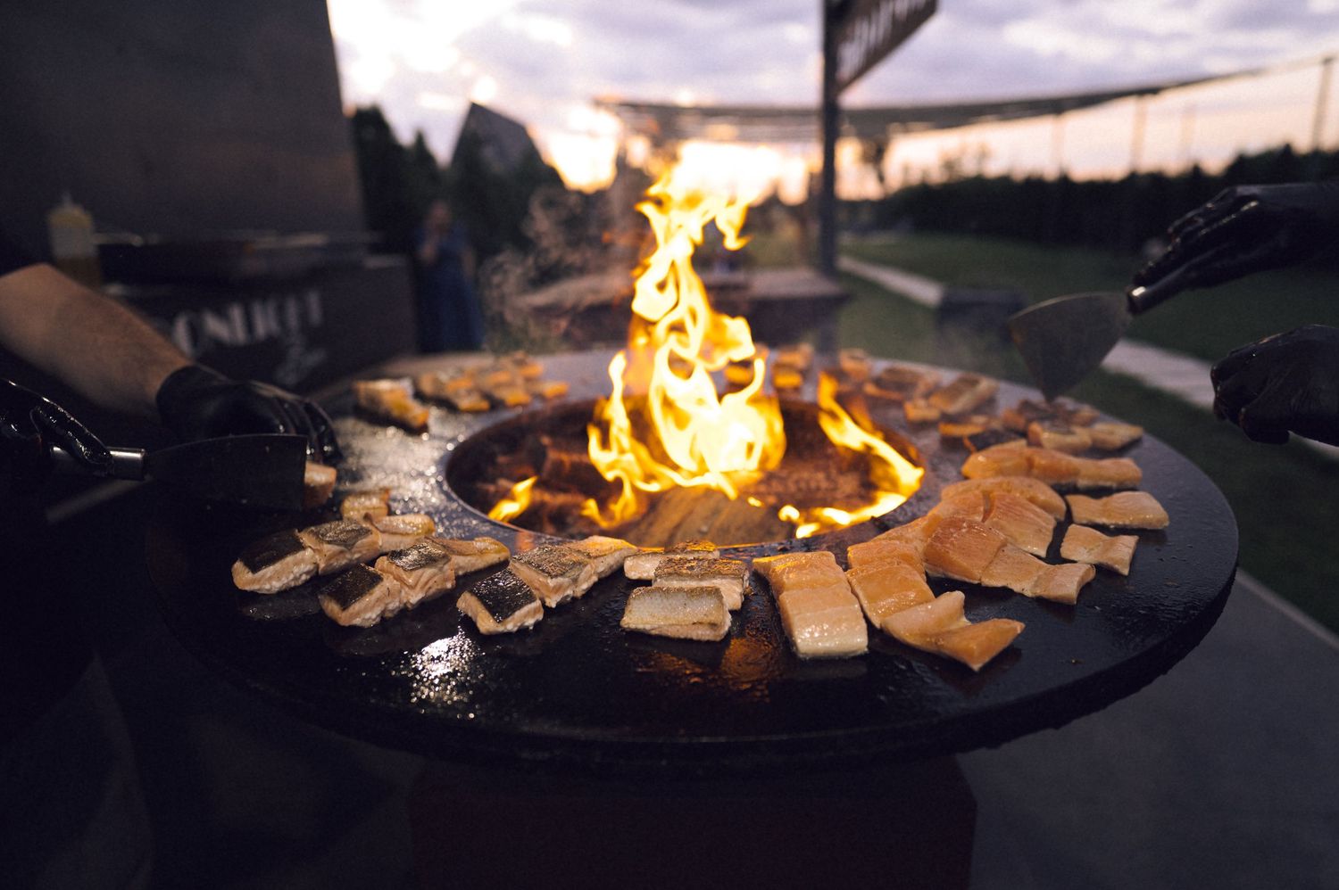 S'mores ingredients arranged around a flaming outdoor fire pit at dusk, perfect for a cozy gathering.