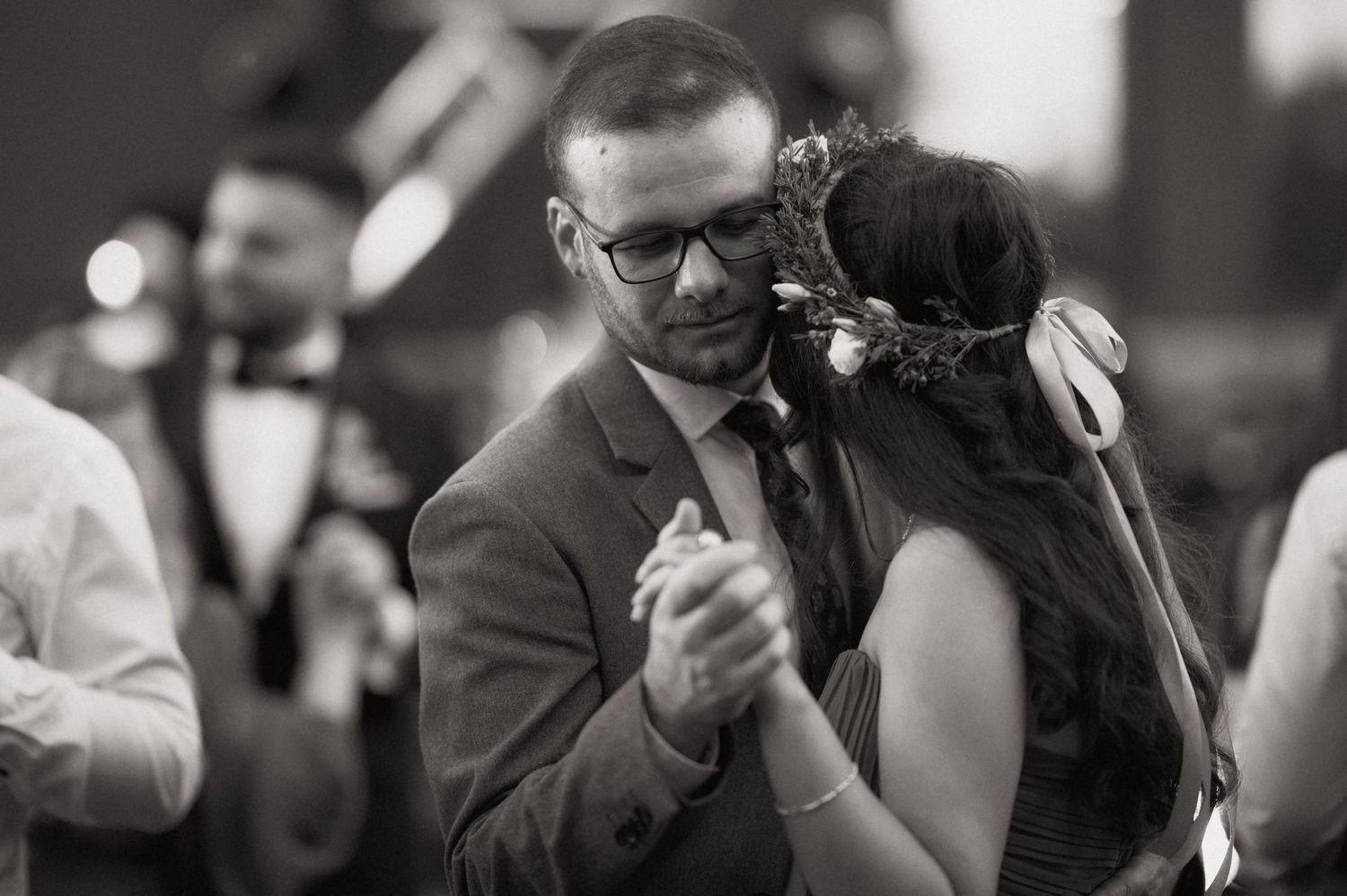 Couple shares intimate first dance in black and white wedding photo with floral hair crown.