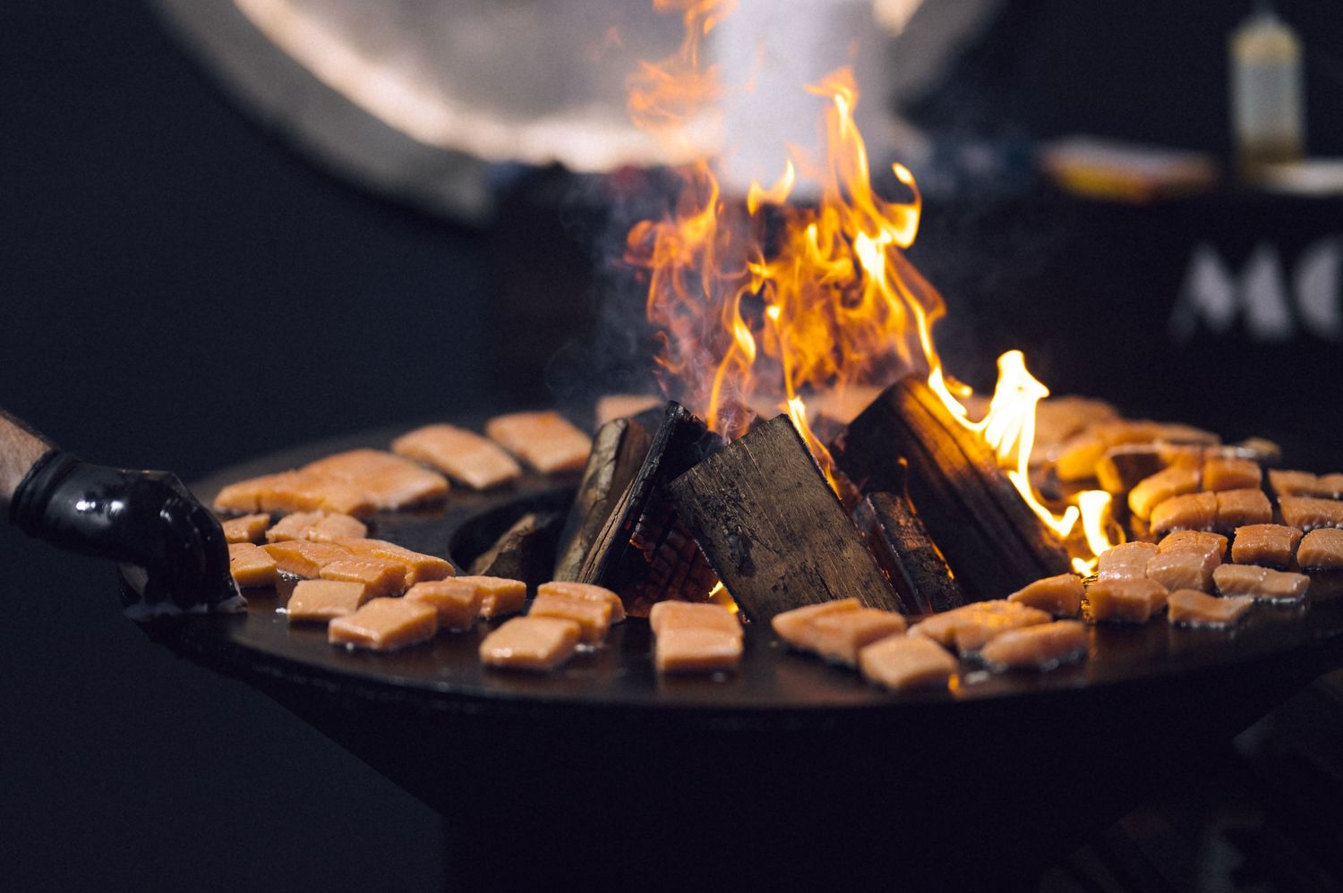 Crackling campfire with golden flames surrounded by toasted bread slices on a dark outdoor grill pan.