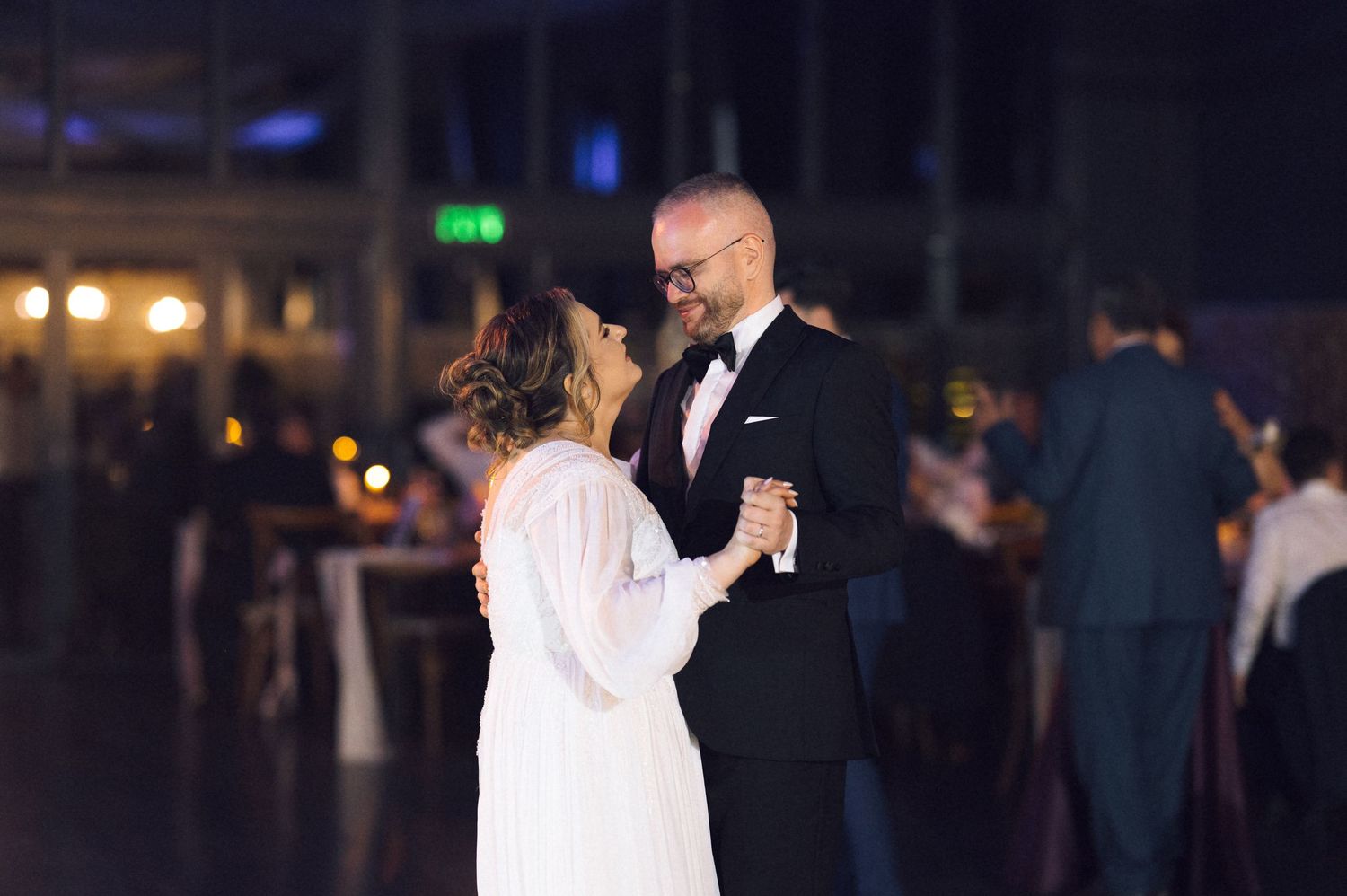 Bride and groom sharing their first dance at a wedding reception in an elegant dimly lit venue.