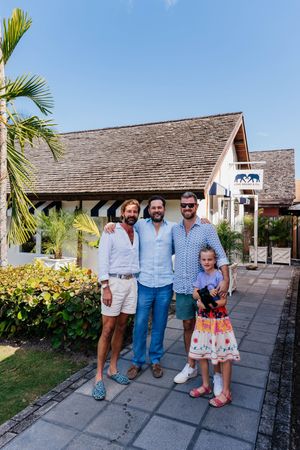 Three men and a young girl posing together outside a tropical Love Brand & Co. store on a sunny day.
