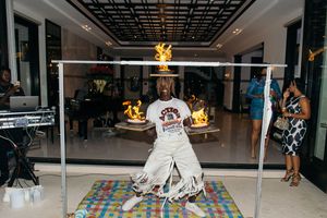 Person in a white outfit surrounded by flames inside a metal frame at an indoor party event.