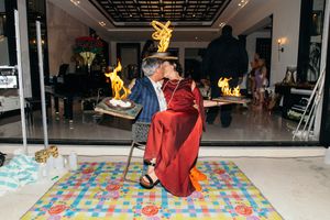 Couple shares romantic kiss surrounded by flaming displays on colorful dance floor at elegant indoor celebration.