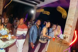 Guests mingle at a vibrant indoor party with colorful neon lights and festive decorations.