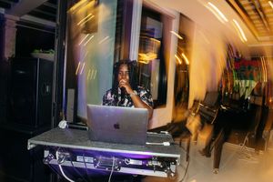 DJ performing at a nightclub event using a MacBook laptop and mixing equipment under dramatic lighting.