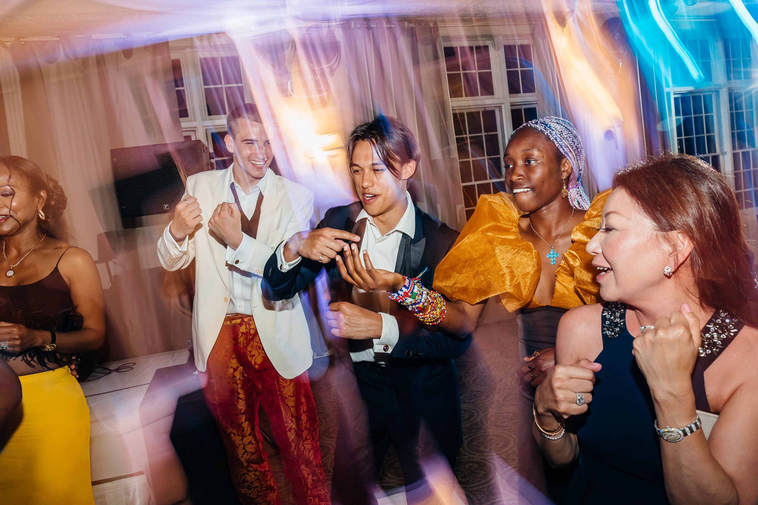 Diverse group of friends dancing and laughing joyfully at a lively indoor party celebration.