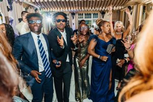 Guests in formal attire dance and celebrate at an elegant wedding reception party.