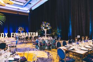 Elegant Fox Foundation gala event with blue floral centerpieces, round tables, and marquee letters in a decorated ballroom.