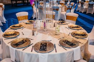 Luxurious gold sequin table setting with crystal centerpiece, charger plates, and elegant place settings for a formal event.