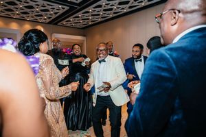 Elegantly dressed guests dancing and celebrating at a formal wedding reception in a decorated ballroom.