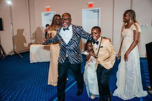 Man in zebra print tuxedo dancing joyfully with children at a formal gala event.