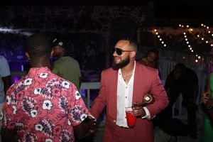 Man in red suit with sunglasses holding drink at outdoor night party event.