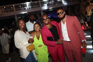 Group of five friends posing together at an outdoor evening party, dressed in vibrant colorful outfits.