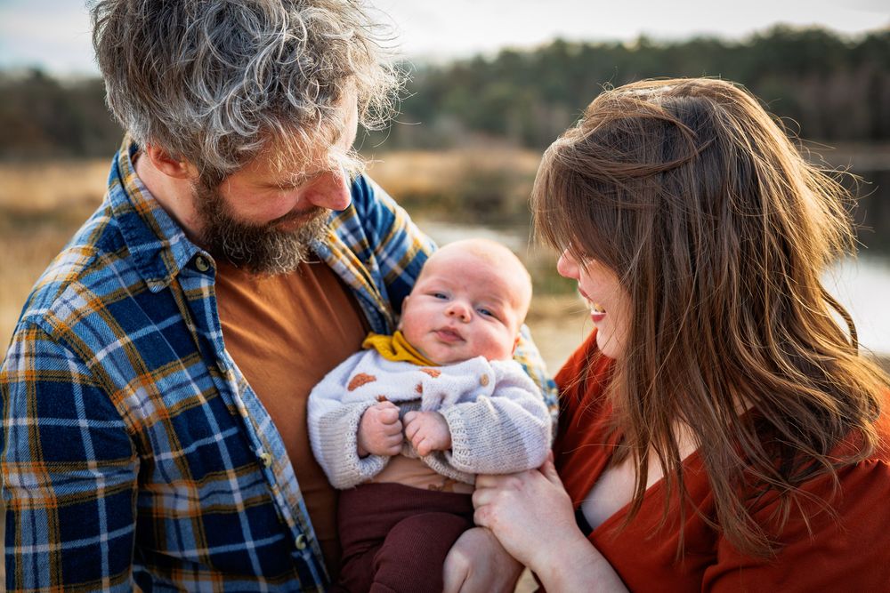 Ouders lachen gelukkig naar baby - new born lifestyle fotografie in de natuur - Sonse vennen - MaxFotos