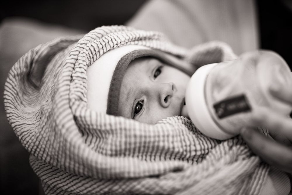 Zwart-wit foto van baby die flesje krijgt - newborn lifestyle fotografie - Sonse vennen - MaxFotos