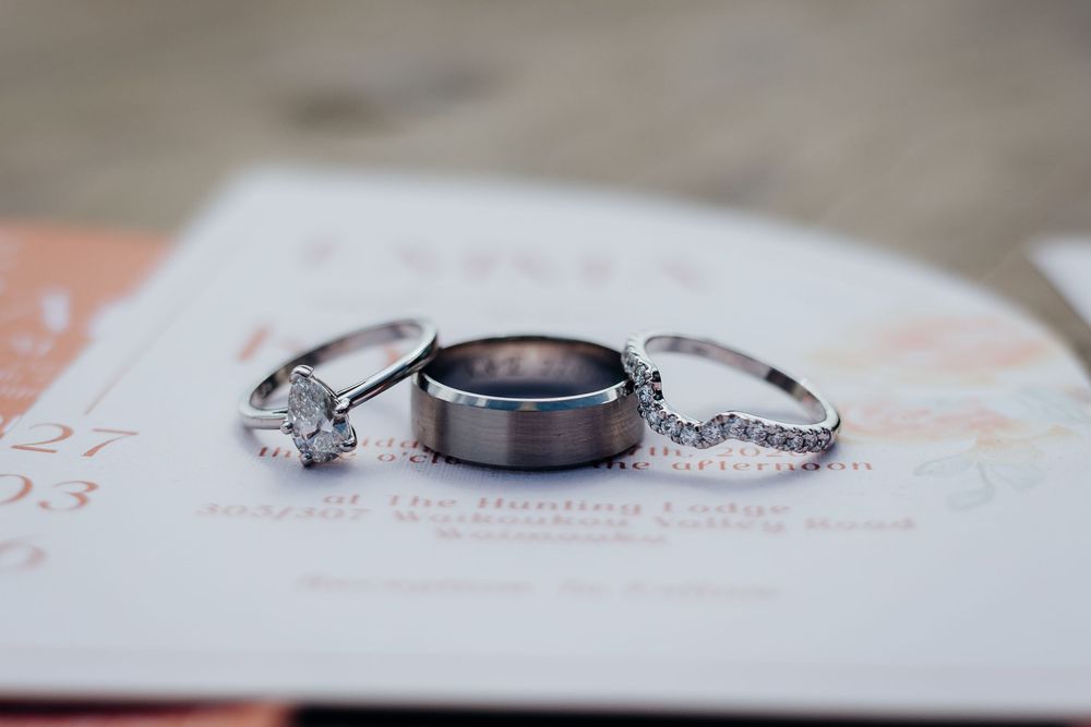 Three wedding rings displayed on a card, featuring a diamond engagement ring, wide tungsten band, and diamond eternity band.