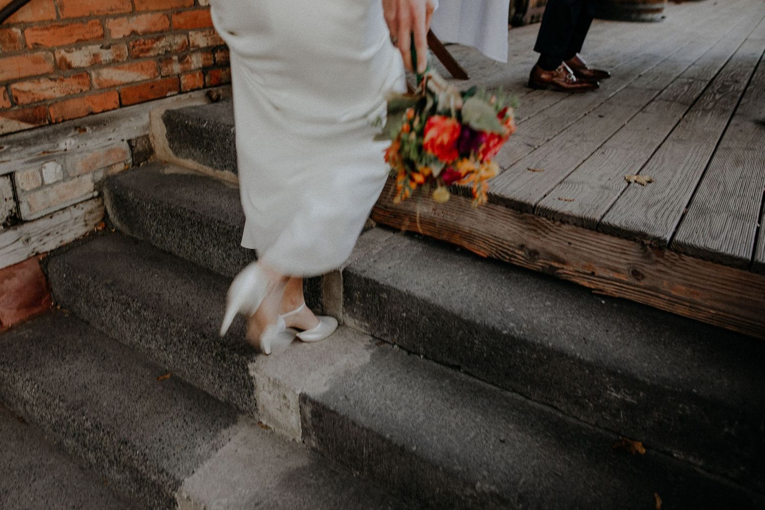 Wedding dress details and floral arrangements on rustic brick steps.