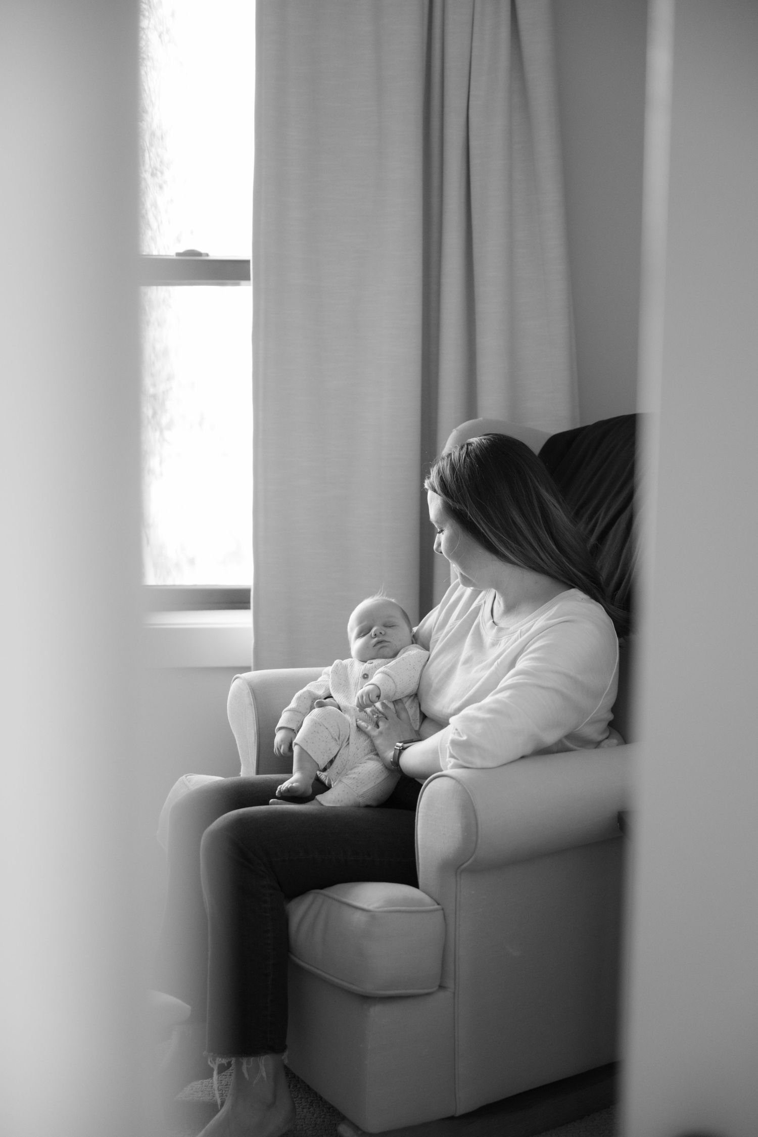 mom and baby snuggling in the nursery while baby falls asleep during in home lifestyle newborn session in woodbury, mn
