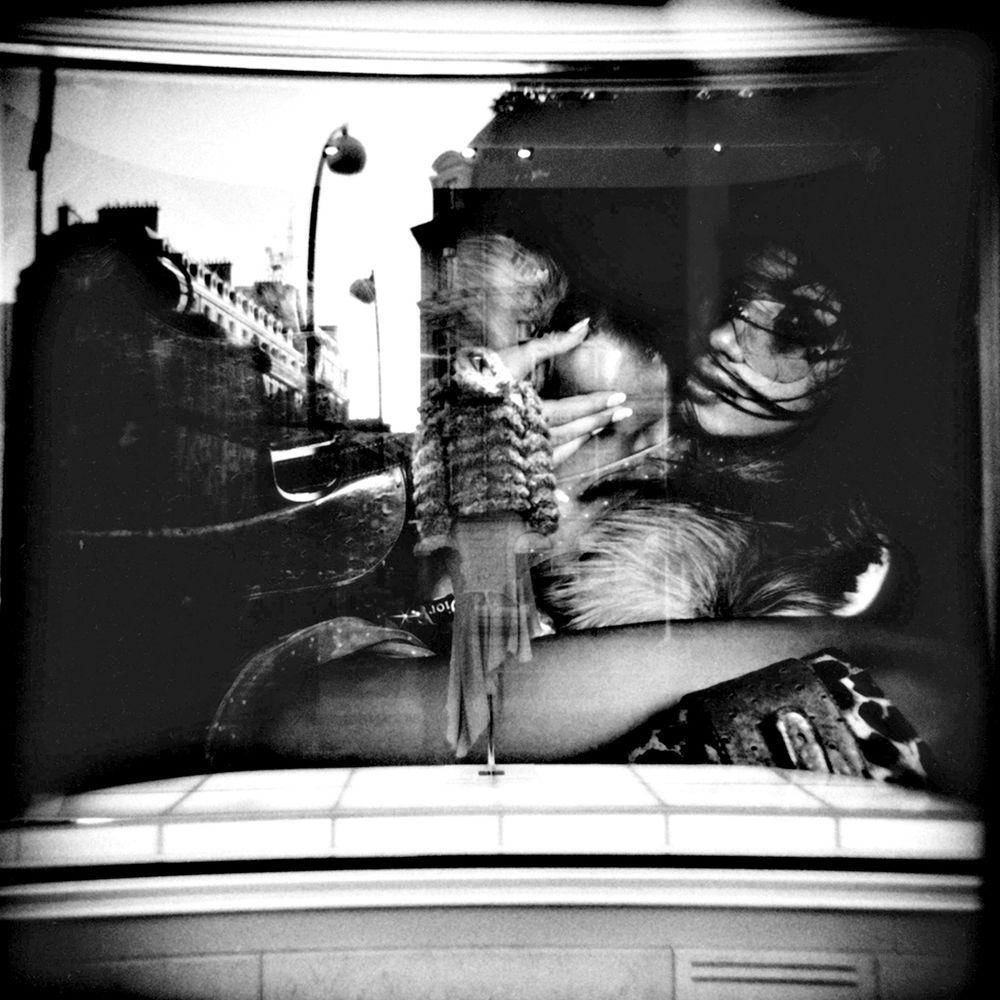 Black and white double exposure photo of two people embracing, overlaid with a city street scene.