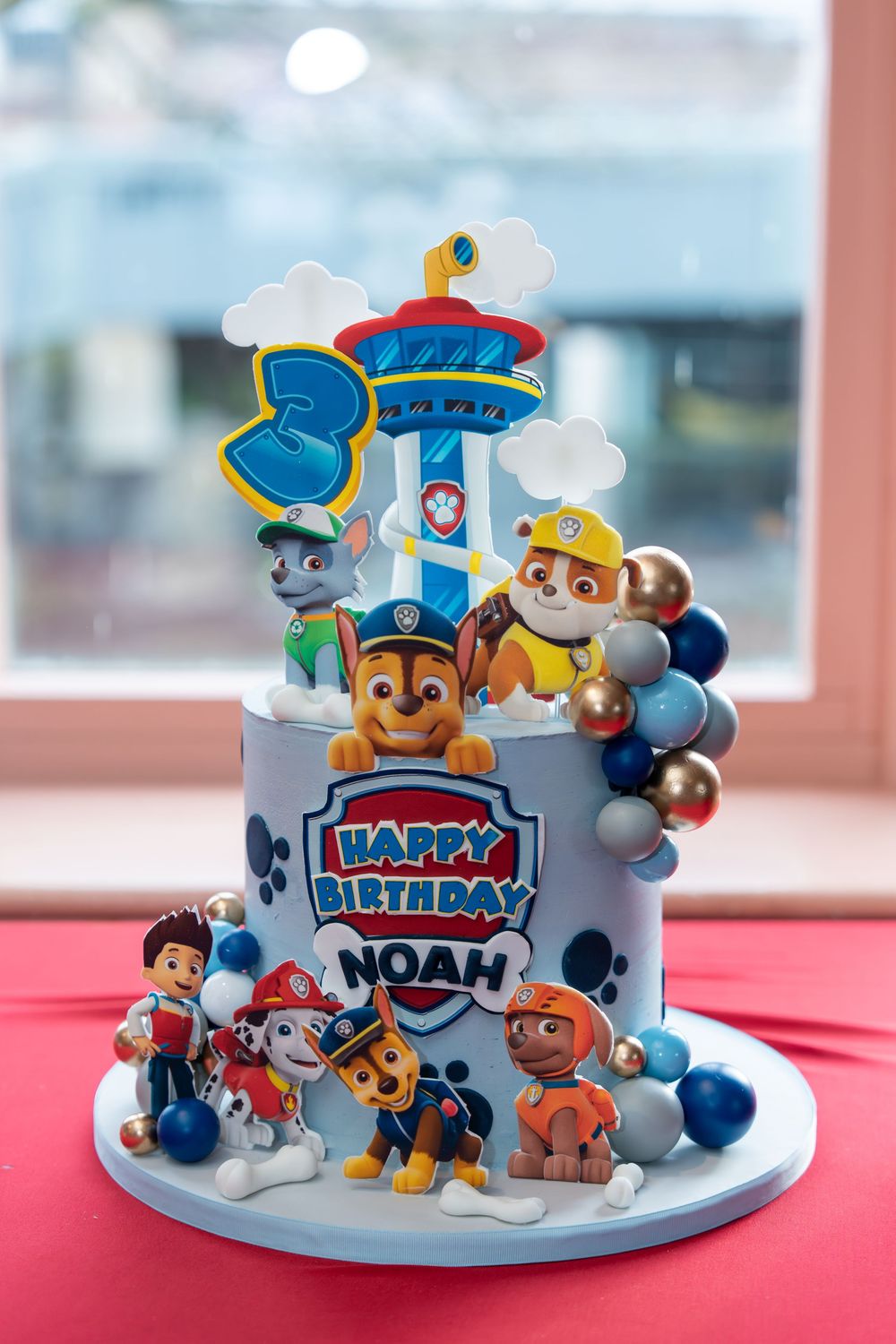 PAW Patrol themed 3rd birthday cake for Noah with character figurines, balloon decorations, and tower topper.