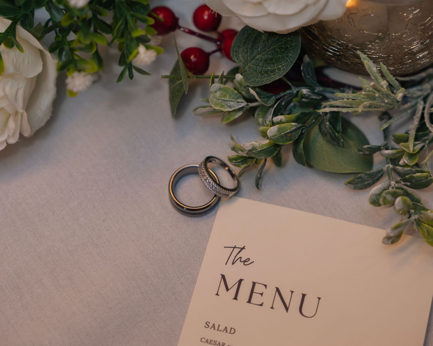 Two wedding rings placed on a menu card with floral decorations.