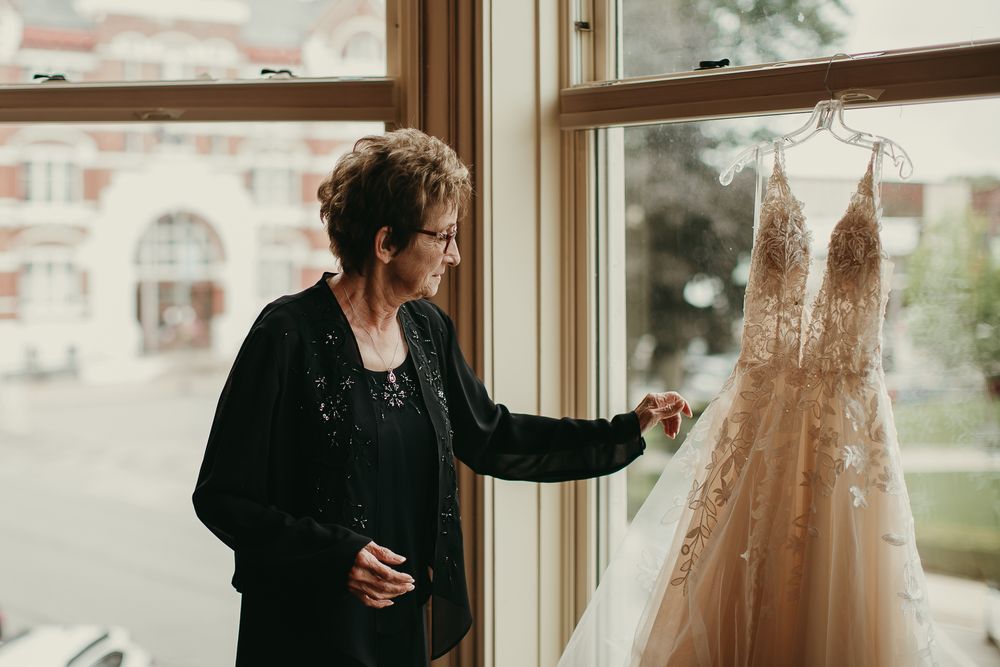 Documentary editorial wedding photography in Iowa by My Muse Weddings showcases a grandmother touching her granddaughters wedding dress.
