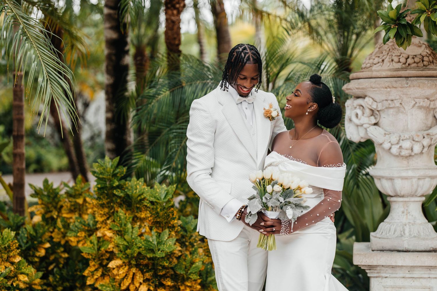 Romantic outdoor wedding ceremony with palm trees and flowing white veil.