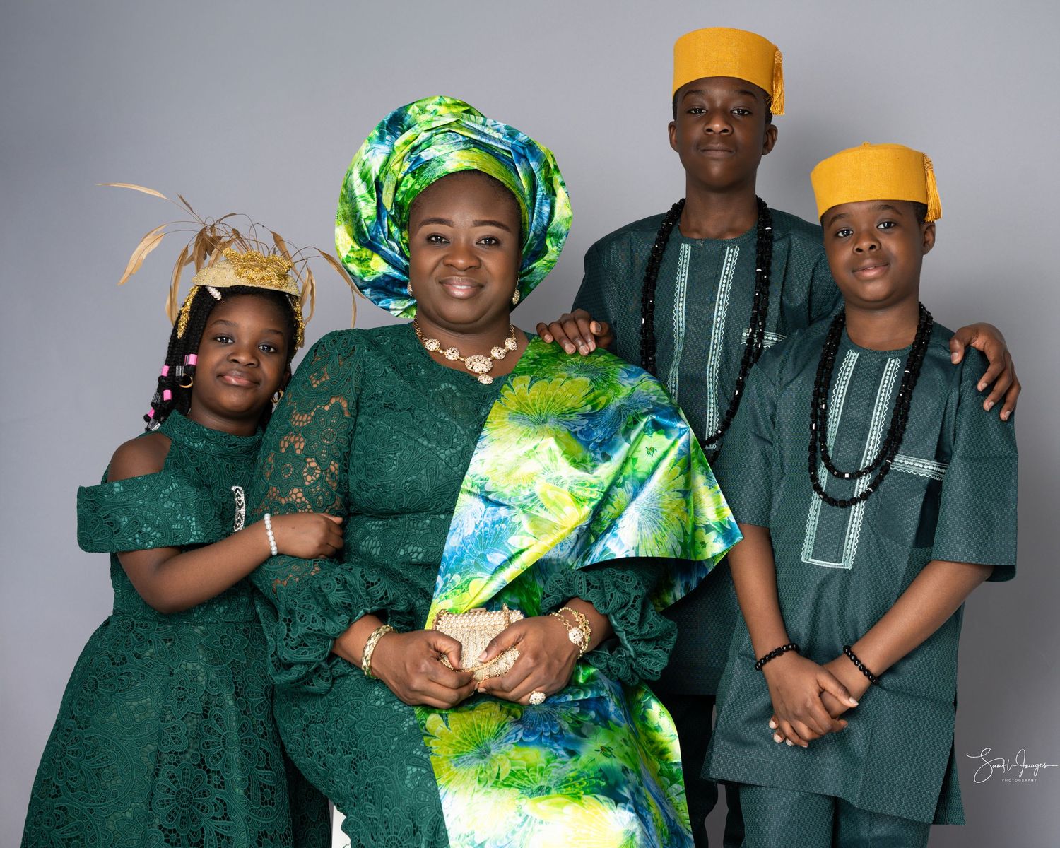 Family of four in matching green traditional Nigerian attire posing for a formal portrait photo.