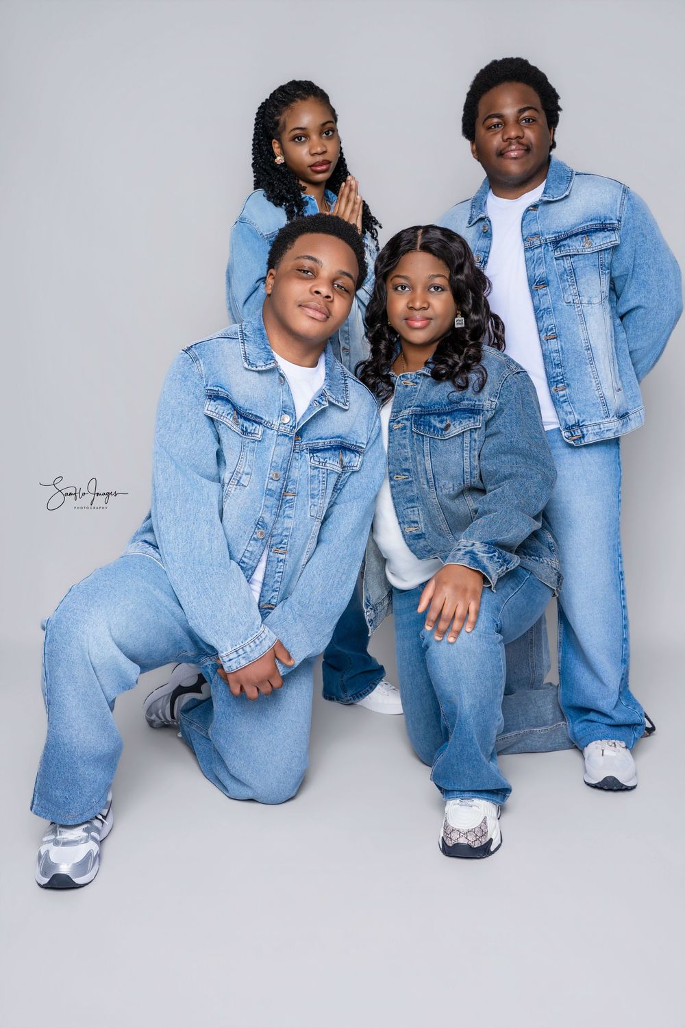 Four children in matching denim outfits pose together for a coordinated family portrait against a gray background.