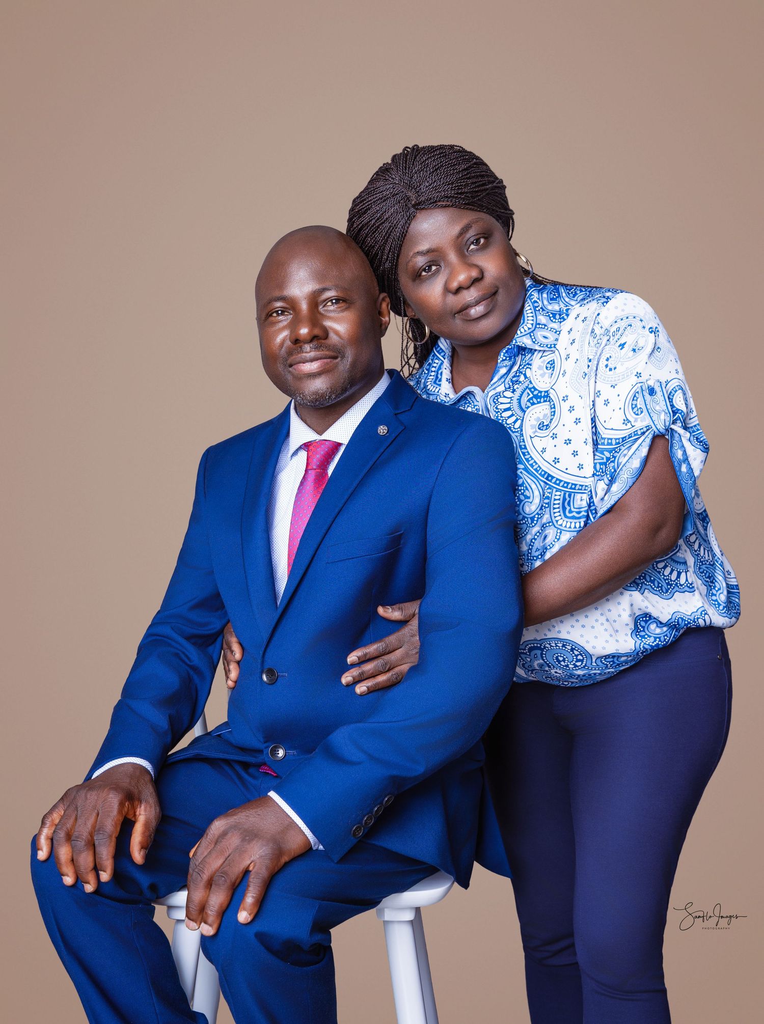 A man in a blue suit and woman in a blue patterned blouse pose together for a professional portrait photo.