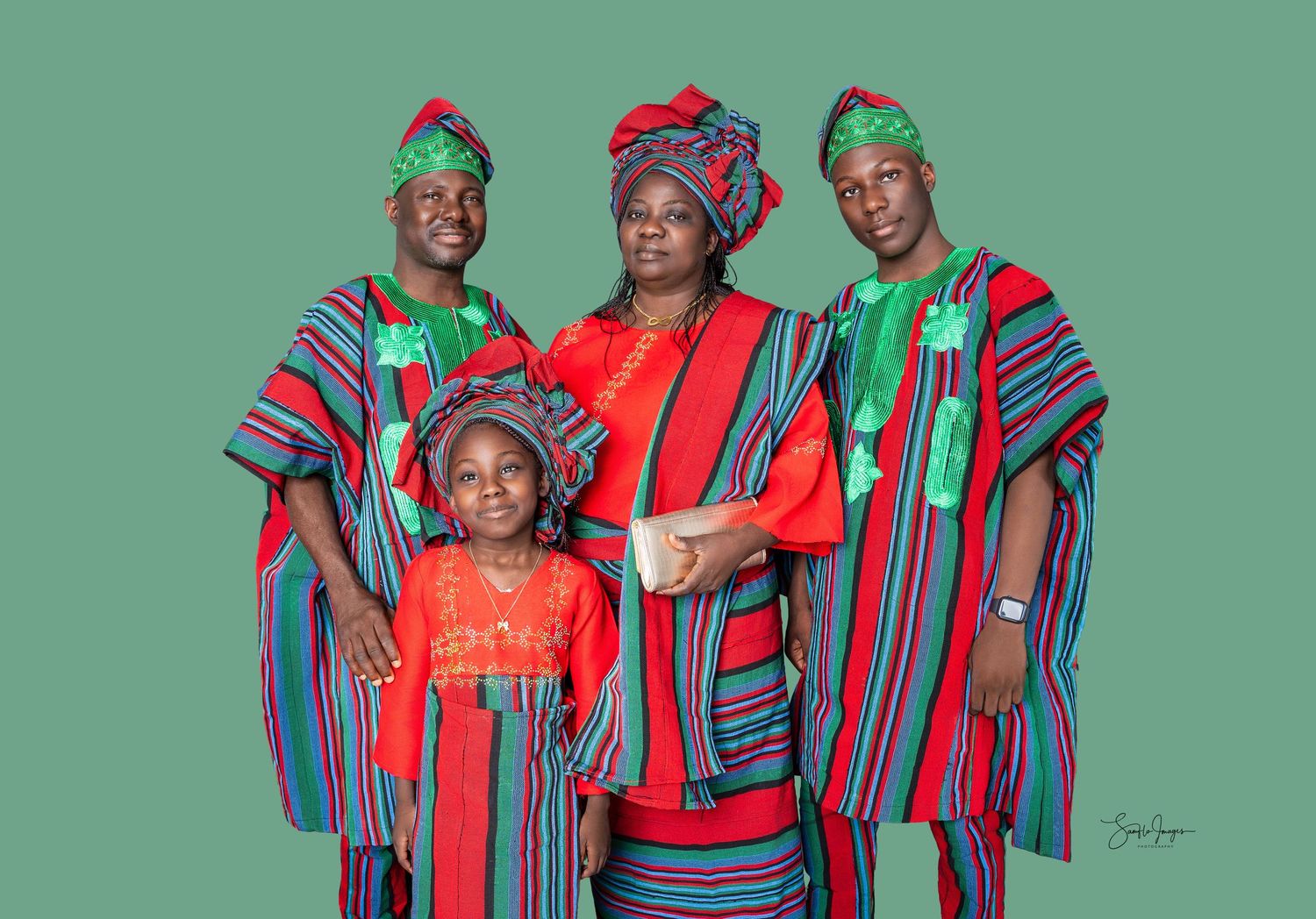 Family of four in matching red and green African traditional attire posing for a portrait photo.