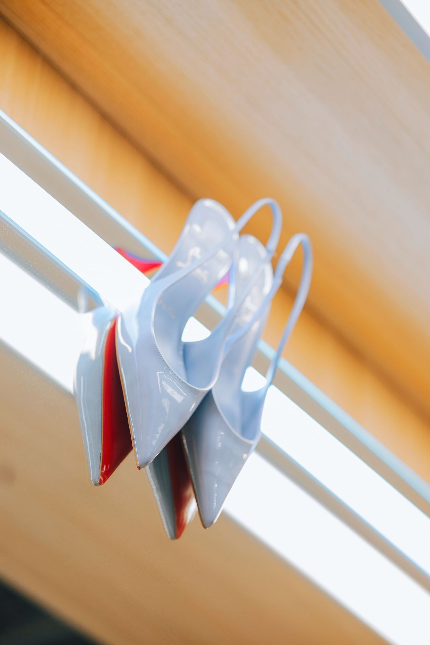Light blue plastic clothes hangers arranged on a metal clothing rack against a wooden background.