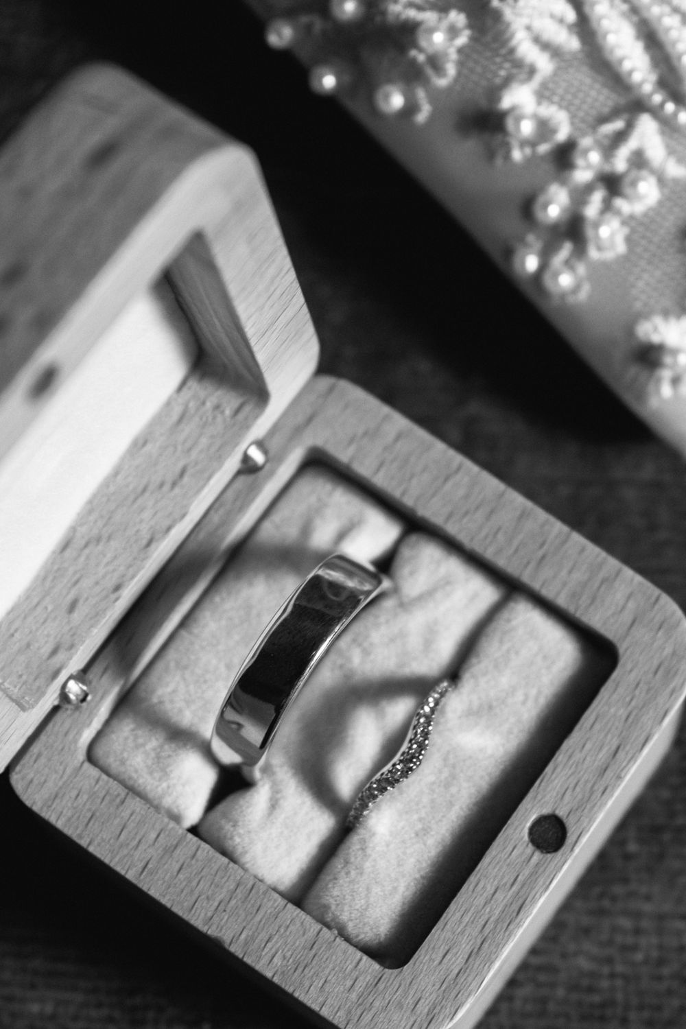 Wedding rings in an open wooden box with velvet lining, black and white photography.