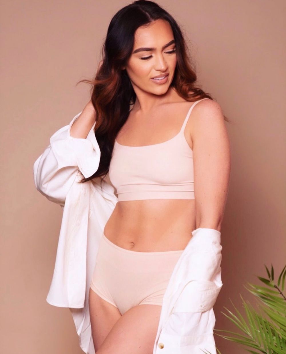 Woman modeling nude seamless bralette and high-waist briefs set, paired with an open white shirt.