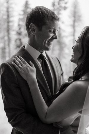 Black and white photo of laughing bride and groom sharing joyful moment at winter wedding.