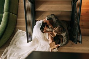 Aerial view of a bride and groom sharing an intimate moment on wooden stairs on their wedding day.