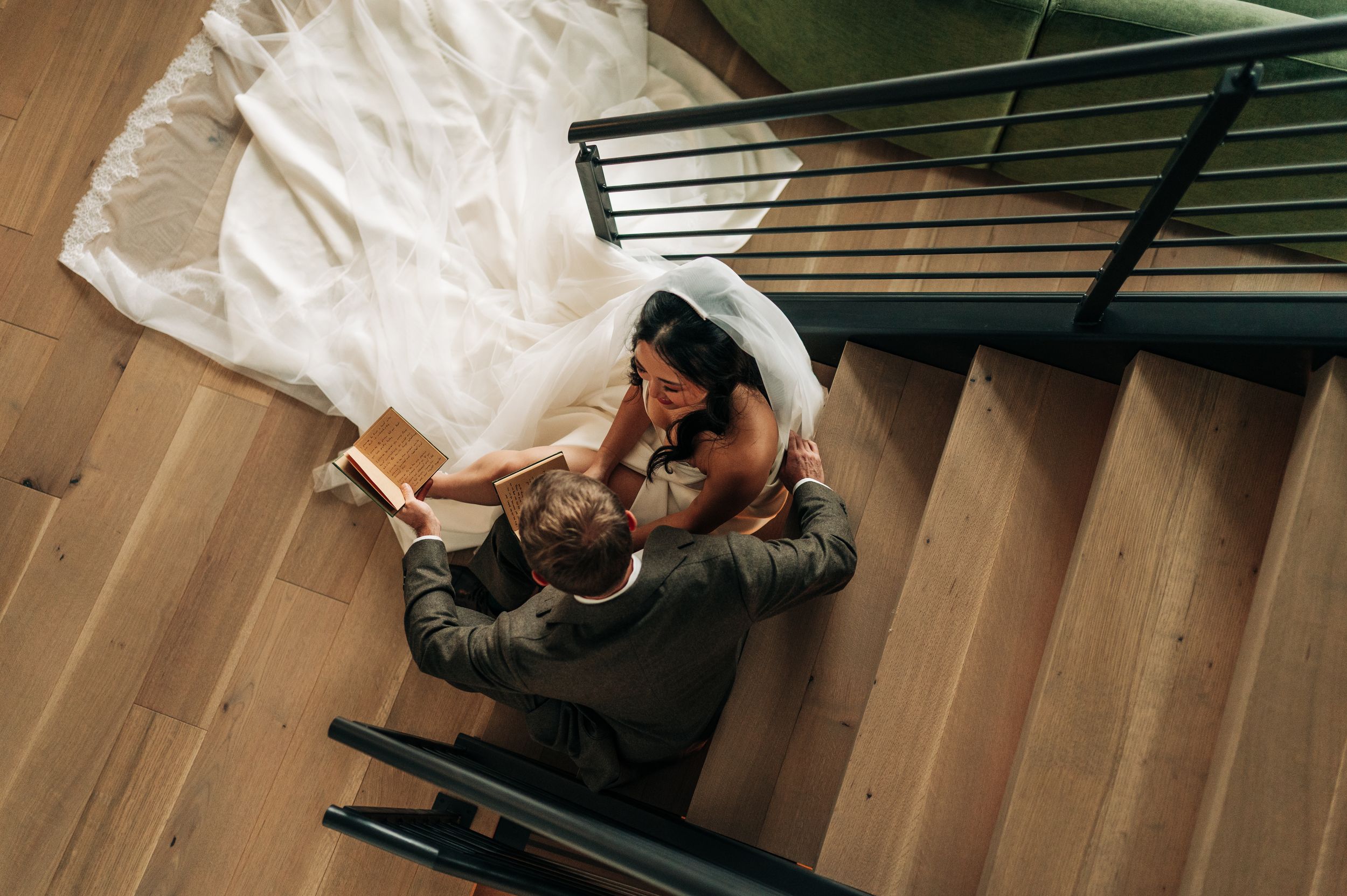 Aerial view of bride and groom sitting on wooden staircase sharing intimate moment.