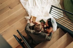 Aerial view of bride and groom sitting on wooden stairs reading their vow books before the ceremony.