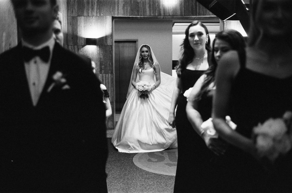 Layered, candid photo of a bride in wedding gown walking with her wedding party before the ceremony.