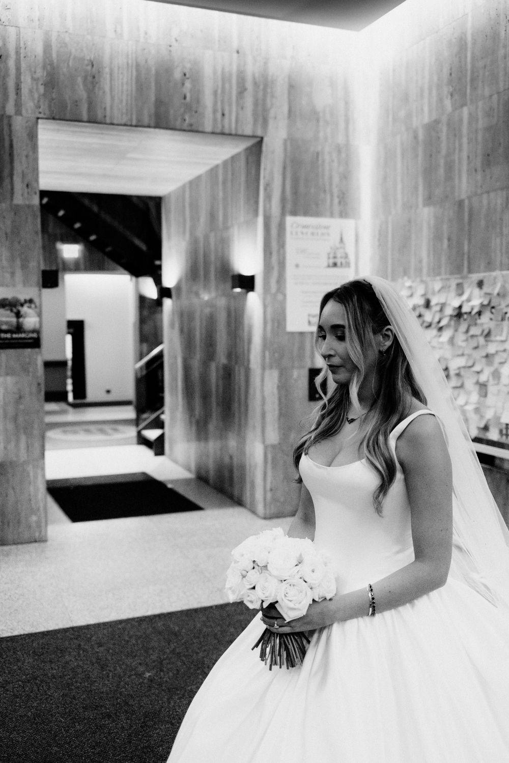 Intimate wedding portrait of a bride holding white rose bouquet wearing elegant gown and veil.