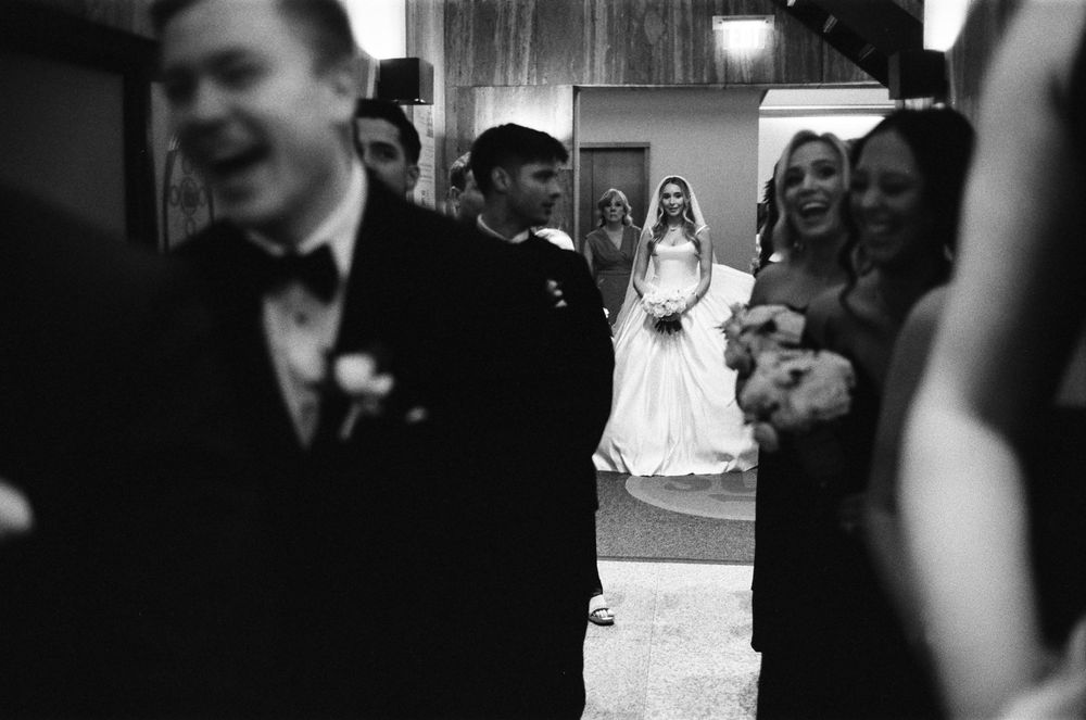 Bride waits in Holy Name Cathedral vestibule surrounded by wedding party before walking down the aisle.