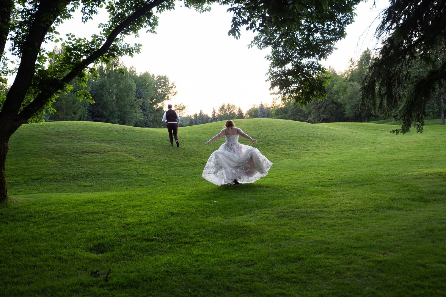 Couple sharing a romantic kiss at sunset with lush forest and dramatic sky in the background at their wedding.