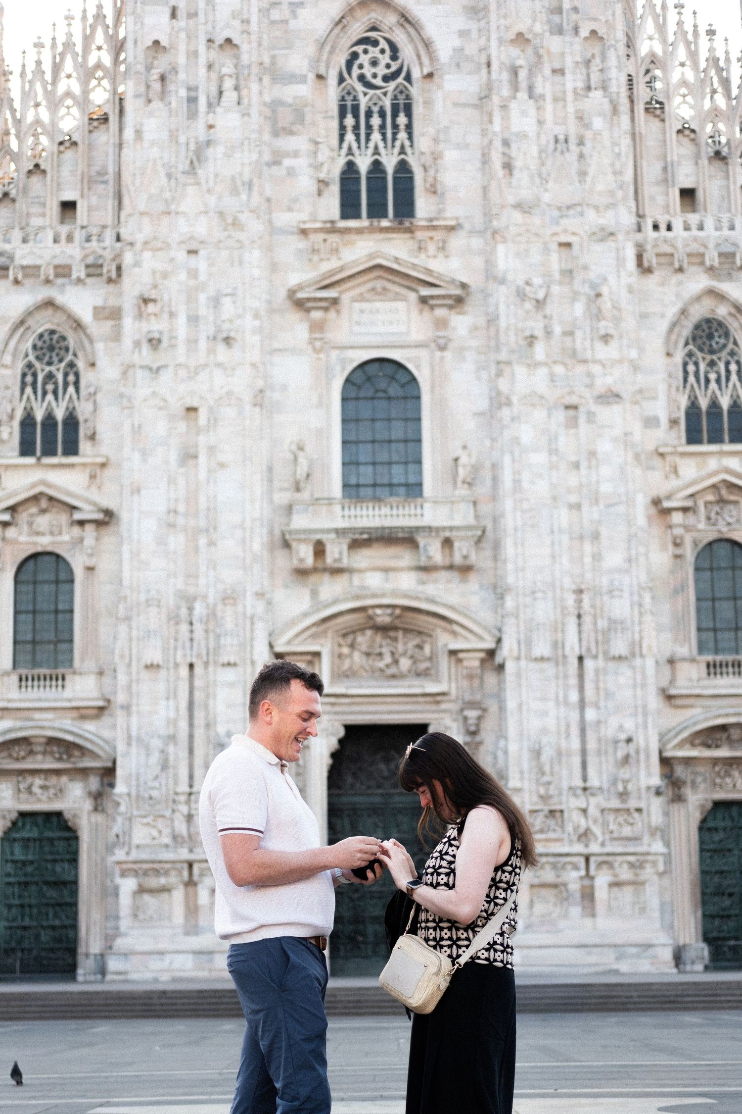 Couple sharing a romantic moment in front of Milan Cathedral, Duomo di Milano, Italy.