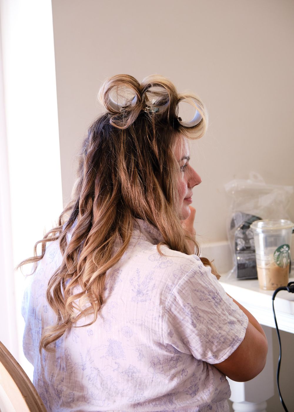 Woman with hair rollers getting curls styled during bridal preparation morning.